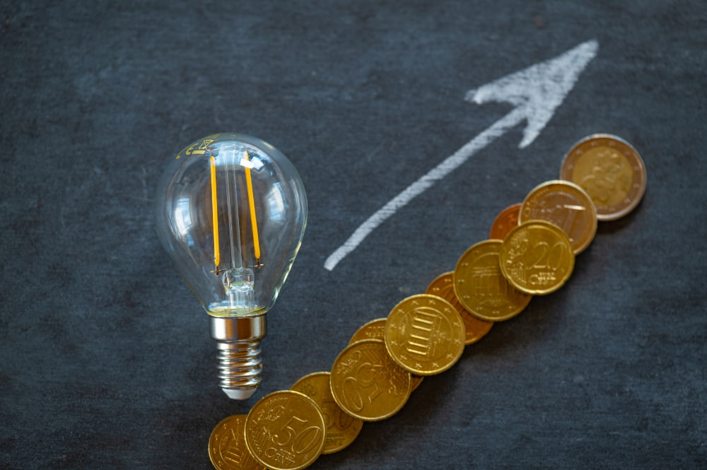 Illustration de la hausse des prix de l'électricité avec une ampoule et des pièces en euros